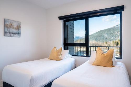 two beds in a room with a large window at Mountainside Revival by Revelstoke Vacations in Revelstoke