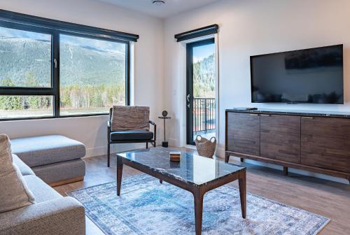 a living room with a tv and a coffee table at Mountainside Revival by Revelstoke Vacations in Revelstoke