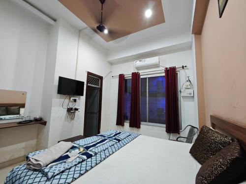 a bedroom with a bed and a tv and a window at Raj Hotel - Since 1960 in Sultānpur