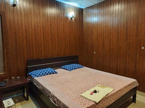 a bedroom with a bed with wood paneled walls at Raj Hotel - Since 1960 in Sultānpur