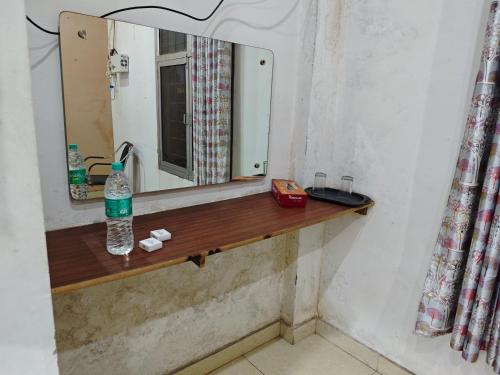 a bathroom with a mirror and a bottle of water on a shelf at Raj Hotel - Since 1960 in Sultānpur