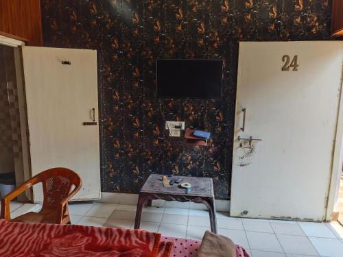 a living room with a table and a tv on a wall at Raj Hotel - Since 1960 in Sultānpur