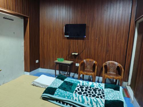 a bedroom with a bed with two chairs and a tv at Raj Hotel - Since 1960 in Sultānpur