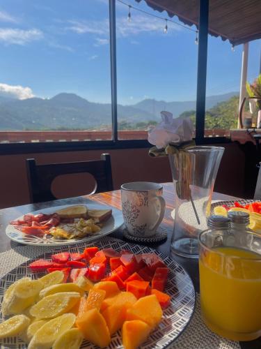 a table with plates of fruit and a glass of orange juice at Dreams Lodge Orosi in Cartago