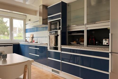 une cuisine avec des armoires bleues et argentées et une table dans l'établissement Quiet 3 bedrooms apt, 30 min from Paris centre, à Bagnolet