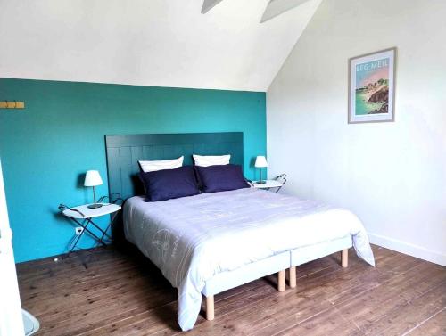 une chambre avec un grand lit avec un mur bleu dans l'établissement Cottage du Cap, à Fouesnant