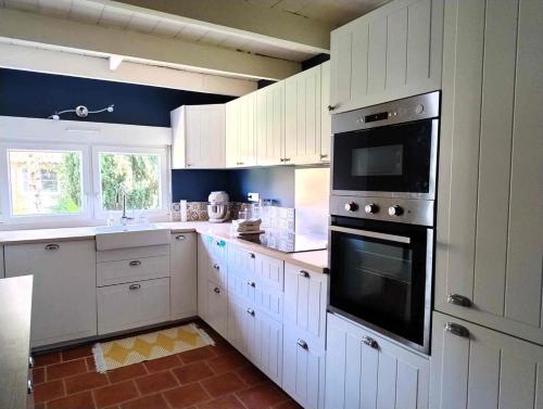 une cuisine avec des armoires blanches et un four à plaques de cuisson dans l'établissement Cottage du Cap, à Fouesnant