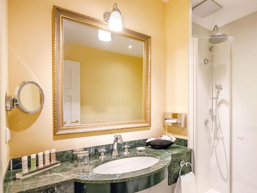 a bathroom with a sink and a mirror and a shower at ROEWERS Privathotel & Spa in Ostseebad Sellin