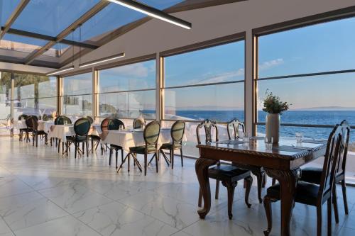 a dining room with tables and chairs and a view of the ocean at Mythical Coast Wellness Retreat in Mytilini