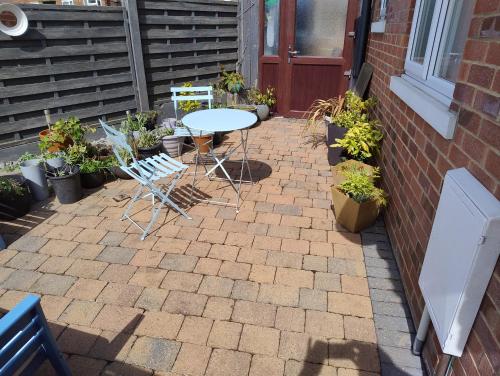 a patio with a table and chairs and potted plants at cosy annex close to leeds airport in Guiseley
