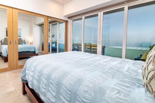 a bedroom with a large bed and large windows at Beachfront Condo with Balcony amazing view in Tijuana