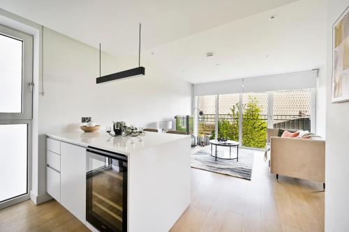 a white kitchen with a counter and a dining room at Luxurious White City Apartment - Balcony & View in London