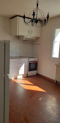 une cuisine avec des armoires blanches et un lustre dans l'établissement Grand appartement à Thouars, à Thouars