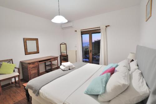 a bedroom with a large white bed and a window at Villa Pefka in Skiathos