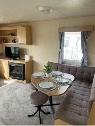 a living room with a table and a couch at 3 Bedroom Caravan - Sleeps 8 - Parking Wifi Pool in Clacton-on-Sea