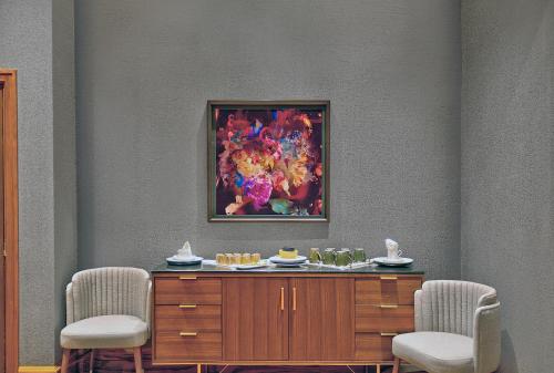 einen Tisch mit zwei Stühlen und ein Gemälde an der Wand in der Unterkunft Le Méridien St. Louis Downtown in Saint Louis