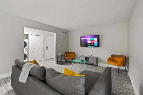 a living room with a gray couch and orange chairs at Stylish & Spacious Getaway Near Downtown in Rochester Hills