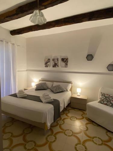 a white bedroom with two beds and two lamps at La casa di Anna in Sapri