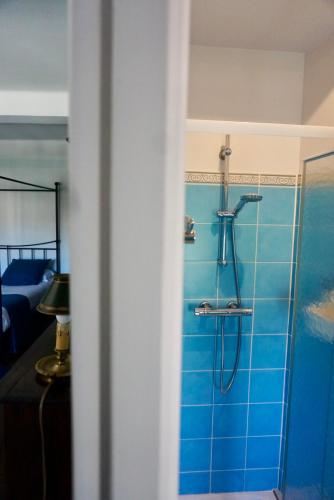 La salle de bains est pourvue d'une douche et d'un mur en carrelage bleu. dans l'établissement La Bastide Saint Etienne, à Cournanel