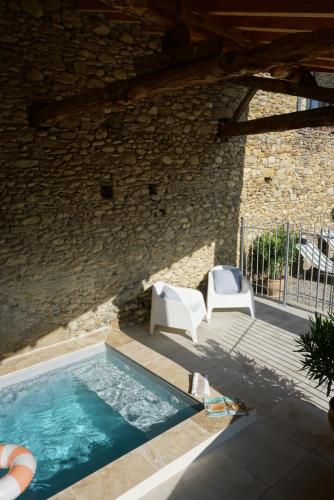 une piscine avec deux chaises et un mur en pierre dans l'établissement La Bastide Saint Etienne, à Cournanel