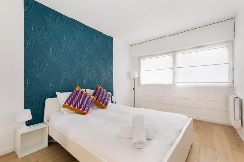 a bedroom with a white bed with a green accent wall at Duplex Cosy 6 personnes - Parking Gratuit - 15 min Centre de Paris Metro 13 in Asnières-sur-Seine