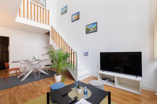 a living room with a large television and a dining room at Duplex Cosy 6 personnes - Parking Gratuit - 15 min Centre de Paris Metro 13 in Asnières-sur-Seine