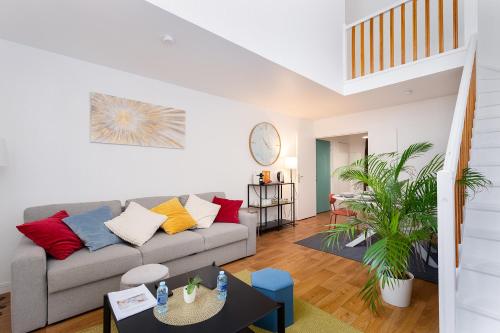a living room with a gray couch with colorful pillows at Duplex Cosy 6 personnes - Parking Gratuit - 15 min Centre de Paris Metro 13 in Asnières-sur-Seine