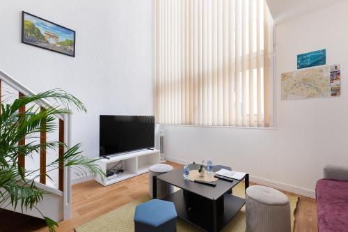 a living room with a tv and a table at Duplex Cosy 6 personnes - Parking Gratuit - 15 min Centre de Paris Metro 13 in Asnières-sur-Seine