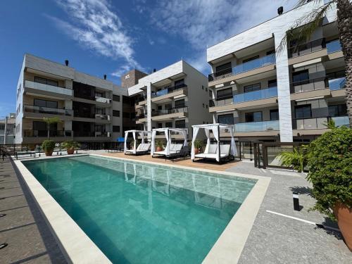 a swimming pool in front of a apartment building at Palmas - Apto de praia moderno em HomeClub a 550m do mar in Governador Celso Ramos