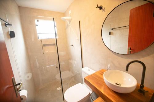 a bathroom with a sink and a shower with a mirror at Suíte Jasmim branco in Campos do Jordão