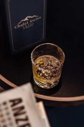 a glass of whiskey on a table next to a book at Hotel Chalet Swiss in Interlaken
