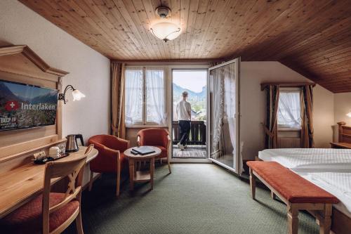 una camera d'albergo con un uomo che guarda fuori dalla finestra di Hotel Chalet Swiss a Interlaken