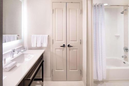 a white bathroom with a shower and a sink at Homewood Suites by Hilton Aliso Viejo Laguna Beach in Aliso Viejo