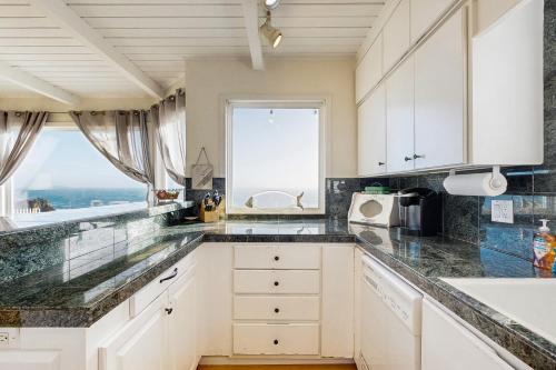 a kitchen with white cabinets and a large window at Sunset Escape in Bodega Bay