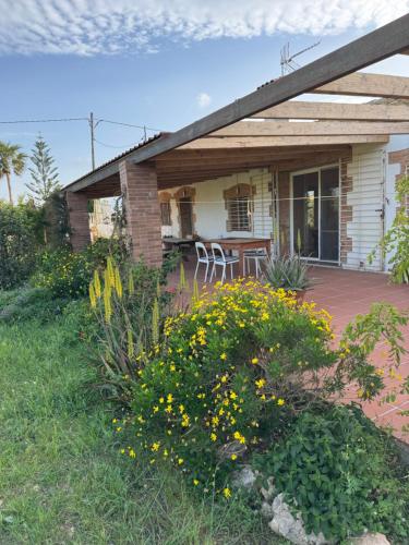 Una casa con patio y algunas flores amarillas. en Masia en el Delta del Ebro, en L'Aldea