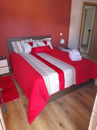 a bedroom with a large bed with red and white sheets at Encanto da Aldeia in Torre de Moncorvo