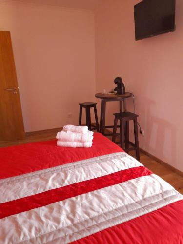 a bedroom with a red and white bed with a table at Encanto da Aldeia in Torre de Moncorvo