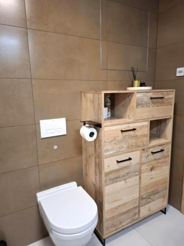 a bathroom with a toilet and a wooden dresser at ORBIS Central apartment in Nitra
