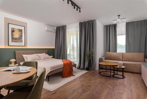 a bedroom with a bed and a couch and a table at Hubix Suites - City of Mara in Timişoara