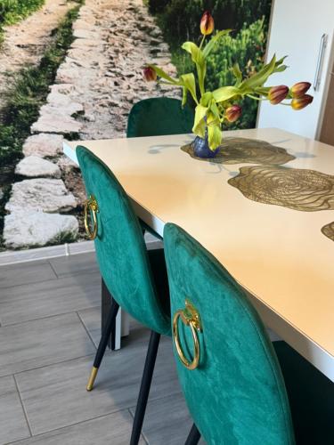 a table with green chairs and a vase of flowers at Domek JuKa in Biały Dunajec