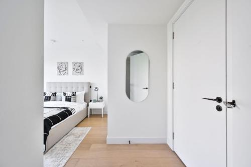 a white bedroom with a bed and a mirror at Stylish White City Apartment - Near Westfield & Tube in London