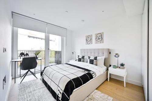 a bedroom with a bed and a desk and a window at Stylish White City Apartment - Near Westfield & Tube in London