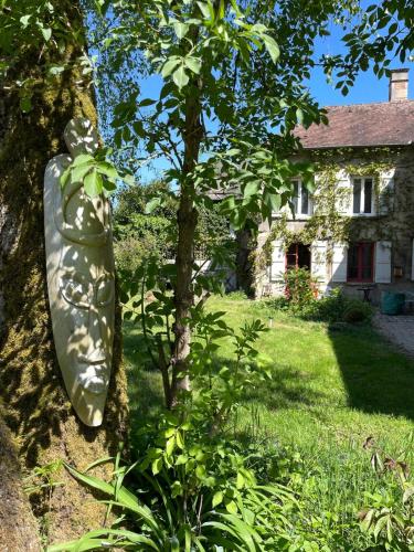 un canoë appuyé contre un arbre devant une maison dans l'établissement Grande Maison Festive, à Loupeigne