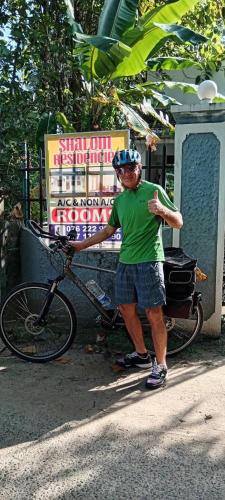 a man with a helmet standing next to a bike at Shalom Residencies in Negombo