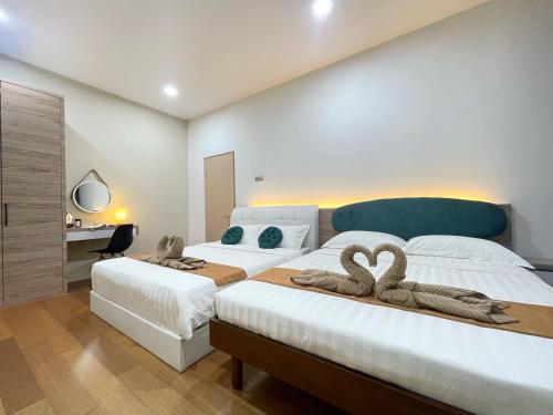 two beds in a bedroom with two swans on them at Ezyhouz - IMAGO The Loft in Kota Kinabalu
