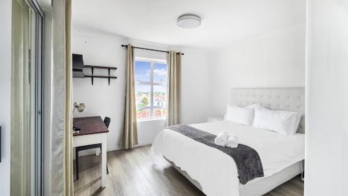 a bedroom with a bed and a desk and a window at Homely 3 Bedroom apartment in Villa Italia Century City in Cape Town