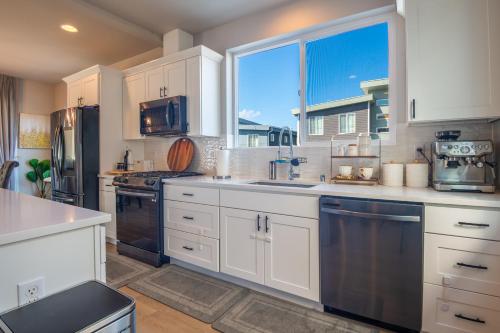 a kitchen with white cabinets and a large window at Utopia Luxury Stay - Lynwood in Lynnwood