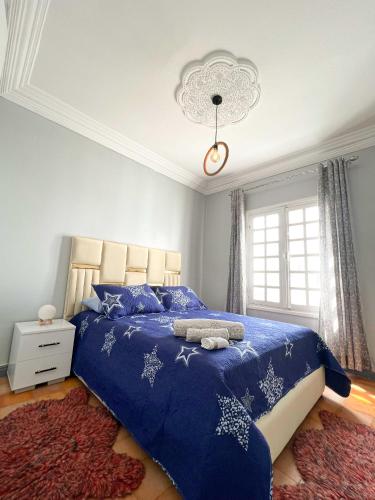 a bedroom with a bed with a blue comforter at An elegant apartment in Essaouira