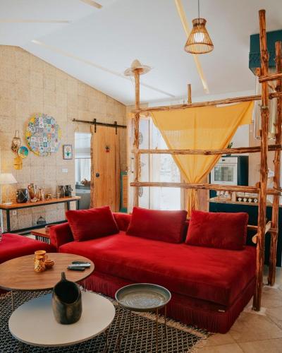 a living room with a red couch and a table at Villa l'Olivier d'Or, Un havre de nature, à deux pas de la mer in Akouda