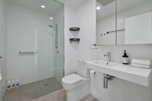 a bathroom with a toilet and a sink and a shower at Cozy 1BR Retreat in Hamilton Near River and Dining in Brisbane